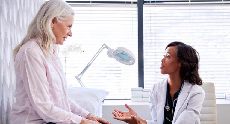 Mature-Woman-In-Consultation-With-Female-Doctor-Sitting-On-Examination-Couch-In-Office-stock-photo2