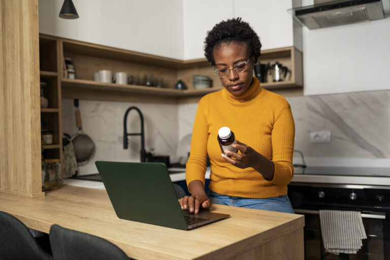 African American woman is looking for information on the internet about the medicine she is holding in her hand stock photo
