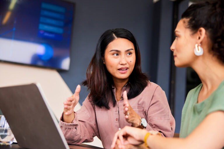 Businesswoman with laptop explaining and gesturing to colleague