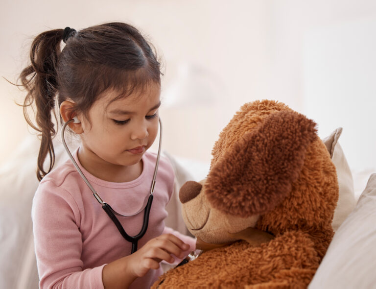 Stethoscope, girl and a teddy bear playing future doctor game showing care on a good health insurance checkup. Cute small child listening or checking stuffed animal medical heartbeat at home
