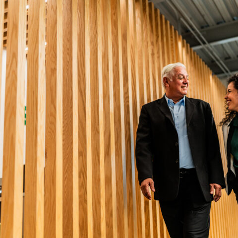 Senior businessman walking and talking with employee at office