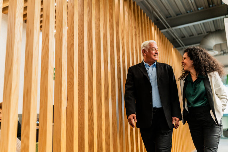 Senior businessman walking and talking with employee at office