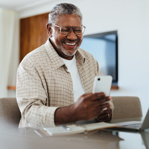 Happy mature male using phone for connecting and staying in touch