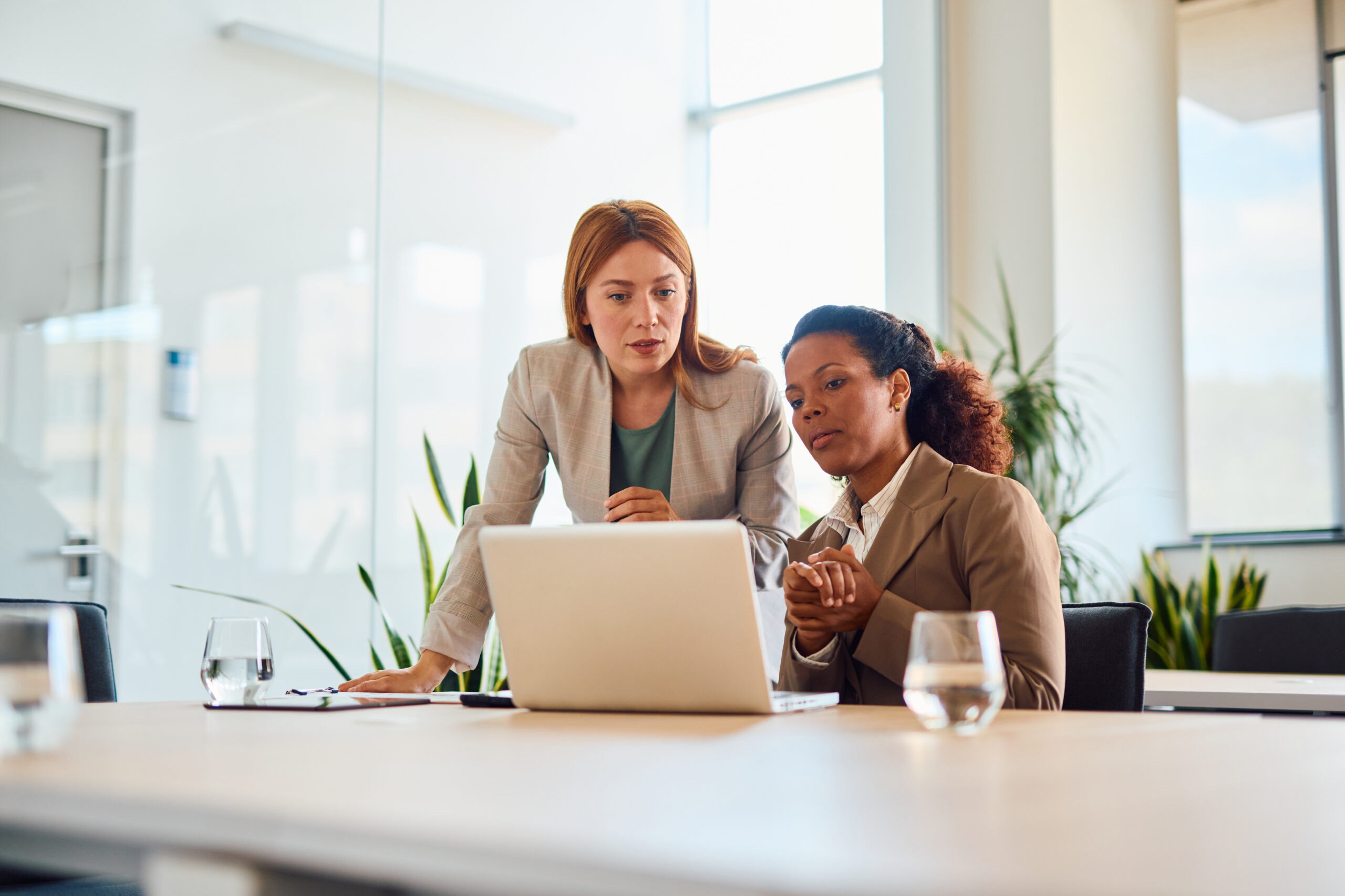 Two businesswomen working together on a laptop in a modern office